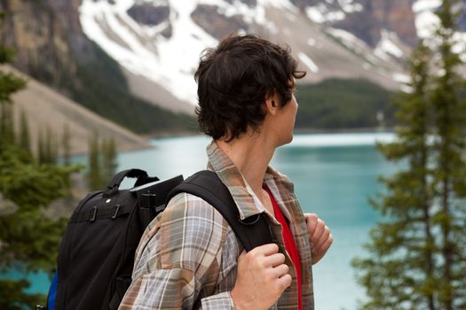 A young man looking out on a beautiful lake and mountain landscape