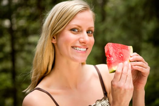 A portrait of a blonde woman eating a watermelon