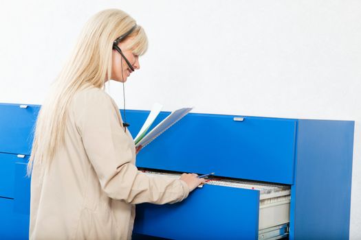 Side view of a young woman searching for documents through a file drawer