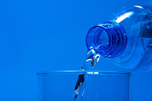 Pouring water from a bottle, blue background