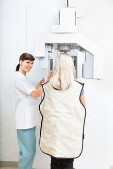 Young female orthodontist taking a panoramic digital xray of a patient`s teeth