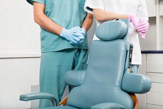 Midsection of a dentist and female assistant in exam room by dentist's chair