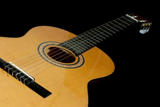 Neck and head of an acoustic guitar, isolated black background with copy-space