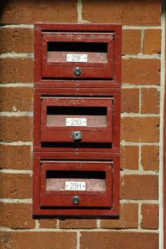 three red mail boxes, brown/orange brick wall