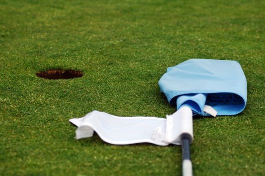 golf green short grass, hole and blue flag post