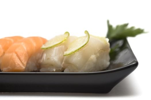 A set of sushi on a black plate with wasabi and gari, isolated on a white background, close-up.