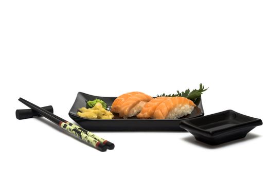 A set of sushi on a black plate with wasabi and gari, isolated on a white background, wish hashi ans soy sauce.