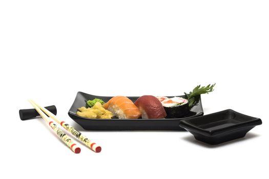 A set of sushi on a black plate with wasabi and gari, isolated on a white background, wish hashi ans soy sauce.