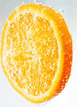 An orange slice covered with and surrounded by bubbles.