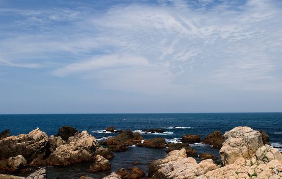 It is a beautiful seascape of rock and blue sea water.