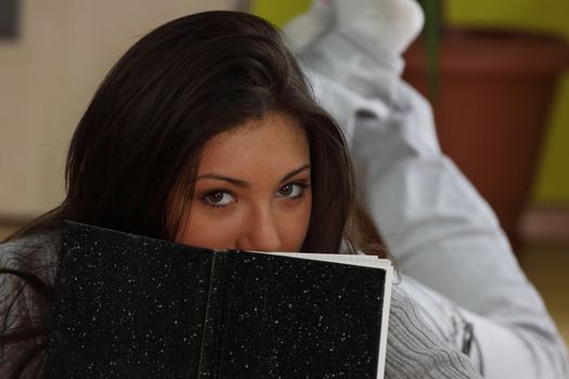 Young beautieful, natural looking, caucasian, brunette girl learning on the flor with red pen and books