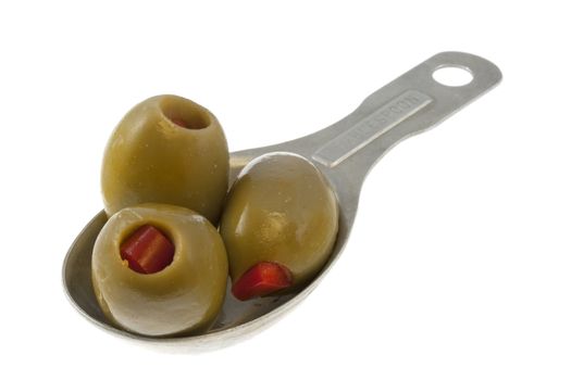 three olives stuffed with pimento on an old aluminum measuring tablespoon isolated on white