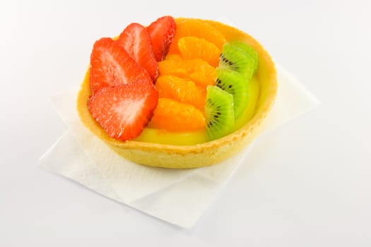 Strawberry, mandarin and kiwi custard fruit tart on a napkin with a white background