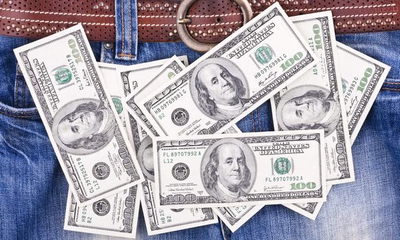 Many hundred dollar bills lying on the blue jeans