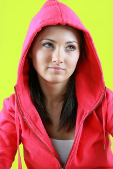 Portrait of young beautiful teen girl in pink hood on green background