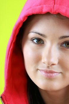 Portrait of young beautiful teen girl in pink hood on green background