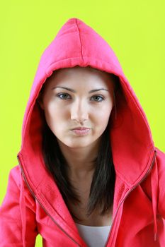 Portrait of young beautiful teen girl in pink hood on green background