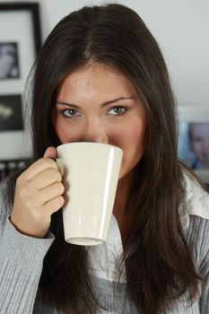 Young woman with beautiful face is having her tea/coffee