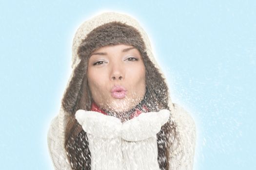 Beautiful winter woman blowing snow kiss. Isolated on blue background. Asian woman.