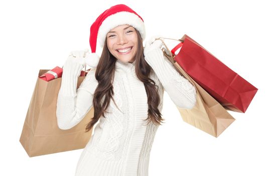 Christmas winter shopping. Woman in santa hat standing holding shopping bags excited isolated on white background. Young mixed race Asian Chinese / white Caucasian model.