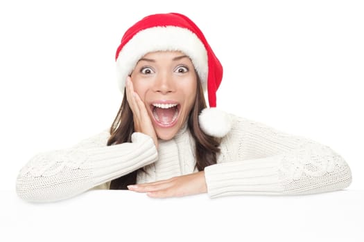 Billboard woman in santa hat leaning on banner for Christmas. Surprised asian beautiful happy model showing blank sign isolated on white background.