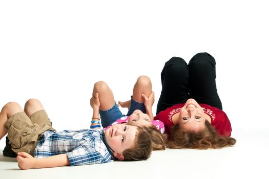 Young brother and sister playing on the floor with thier beautiful mother against a white background.