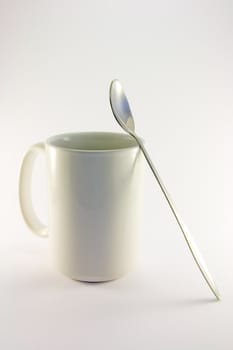 Tall white coffee mug with long spoon on a white background