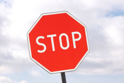 Road sign - stop - on cloudy sky background
