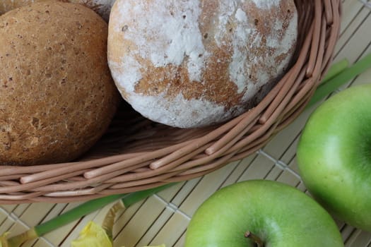 Variety of whole wheat bread in basket and greena apples