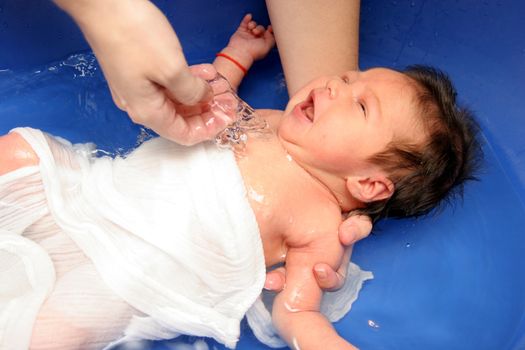 A baby girl in a bathtub at her mother