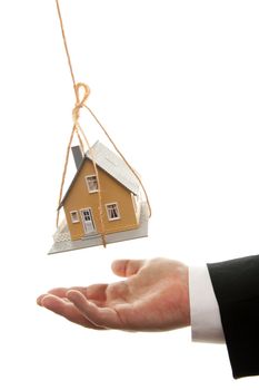 Businessman's Hand Under Dangling House Isolated on a White Background.