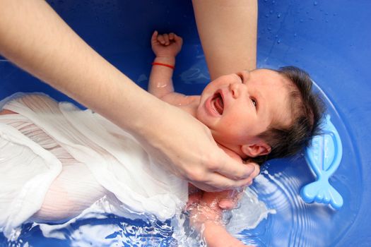 A baby girl in a bathtub at her mother