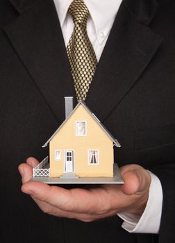 Businessman with Coat and Tie Holding House.