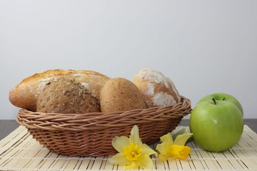 Variety of whole wheat bread in basket and greena apples