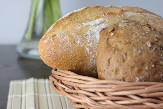 Basket of various fresh baked bread on wooden table