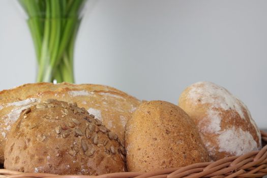 Basket of various fresh baked bread on wooden table