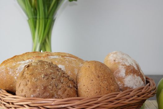 Basket of various fresh baked bread on wooden table