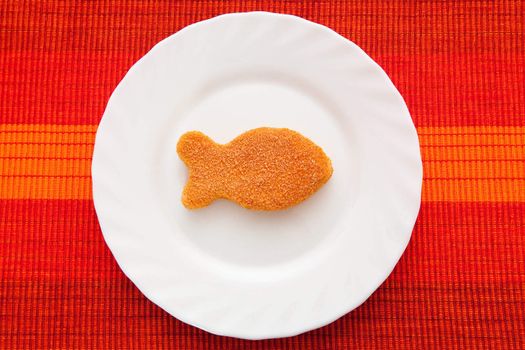 A breaded fish on the white plate