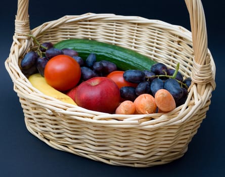 Vegetables and fruits in a basket. Against a dark background.