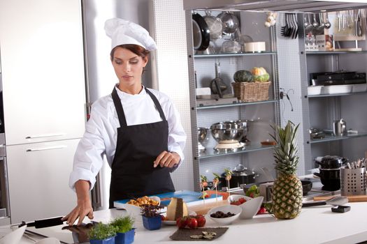 Attractive female chef working in her kitchen preparing the meal