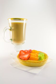 Strawberry, mandarin and kiwi custard fruit tart on a napkin with latte on a  white background