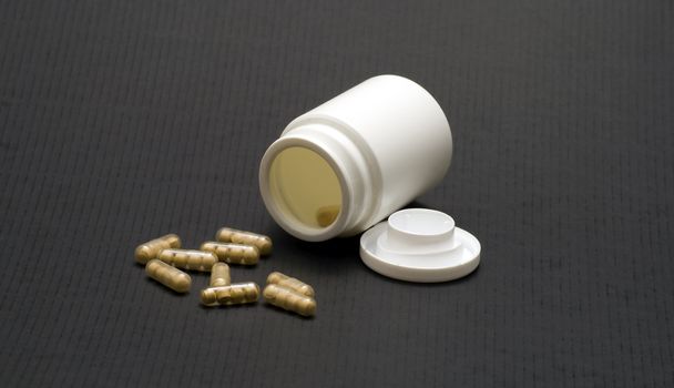 Many pills from a round box on blcak background