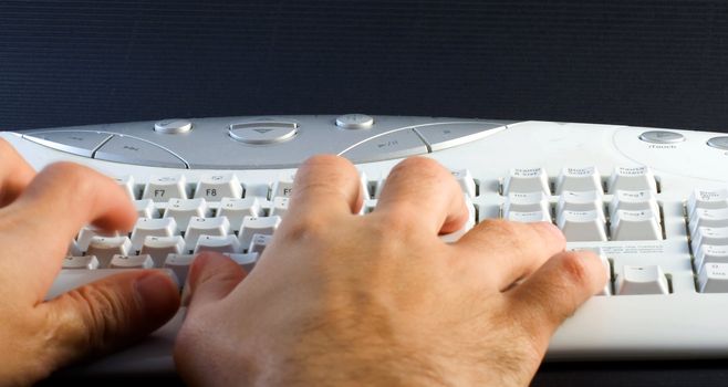 Male hands writing on a computer white and gray keyboard