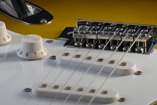 Closeup of electric guitar Stratocaster-type, white and sunburnt, with strings