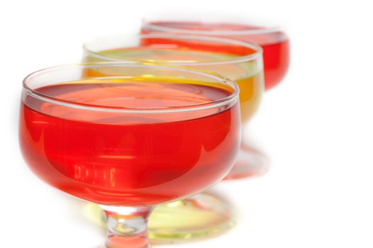 Yellow, red jelly in transparent glass stand on white background inline