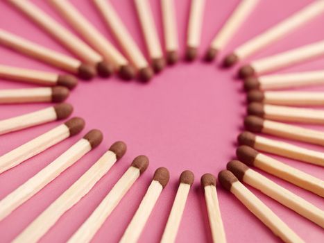 Matches formed as a heart on pink background