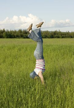 The girl costs head over heels on a green grass in the field