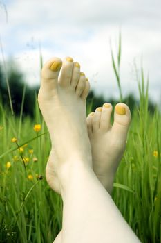 Two female feet against a green juicy grass