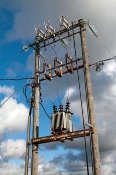 Electric transformer substation against a blue sky with white clouds
