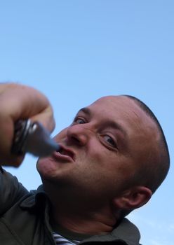 Portrait of a male thug brandishing a pocket knife